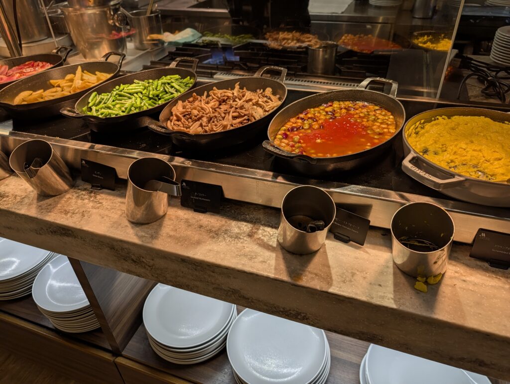 ストウブ鍋に温かい料理が並ぶ朝食ビュッフェのホットミールコーナー