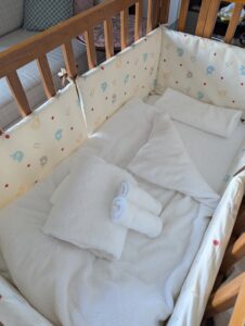 ふかふかの布団とタオルがセットされた安全な木製ベビーベッド