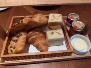 クロワッサンやホテルロゴ入り食パンが入った木製バスケットのパンセット