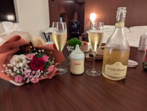 お祝いの花束やシャンパングラスとともに置かれたピジョンの哺乳瓶