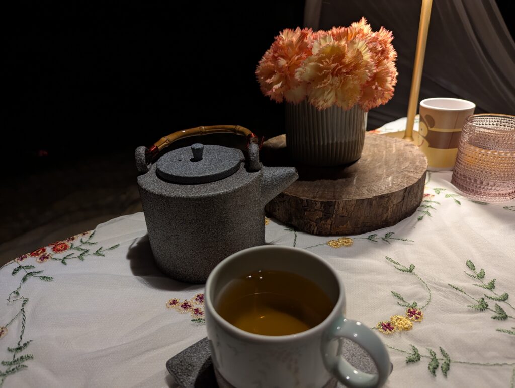 木製スタンドと生花が飾られたビーチテーブルで楽しむ食後の温かいお茶